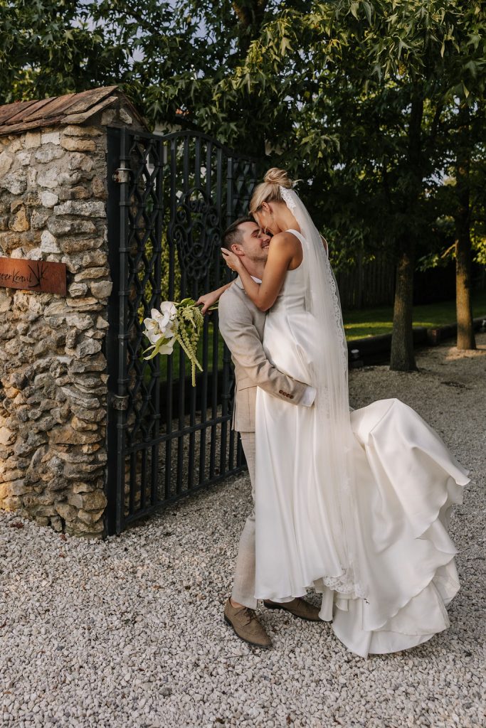 Brautpaar umarmt sich romantisch vor Gartentor – Hochzeitsfotograf Düsseldorf hält intimen Moment fest