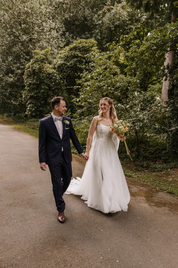 Während dem Brautpaarshooting läuft das Brautpaar Händchen haltend durch den Park Solingen