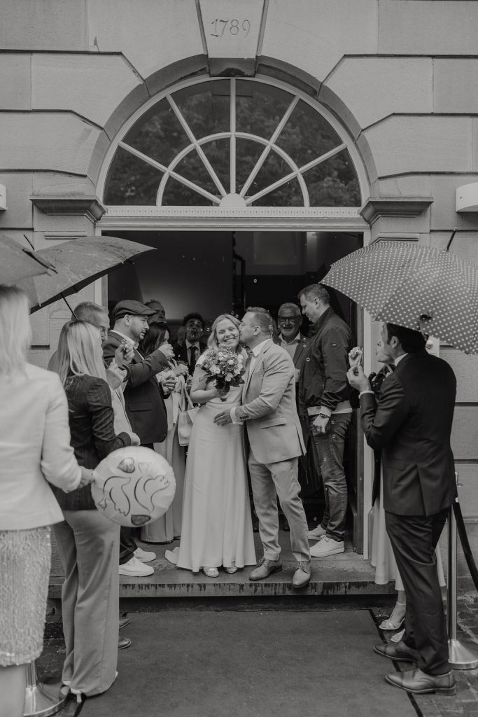 Auszug nach der Standesamtliche Hochzeit, Brautpaar gibt sich mitten in den Gästen einen Kuss und wird im Seifenblasen gefeiert
