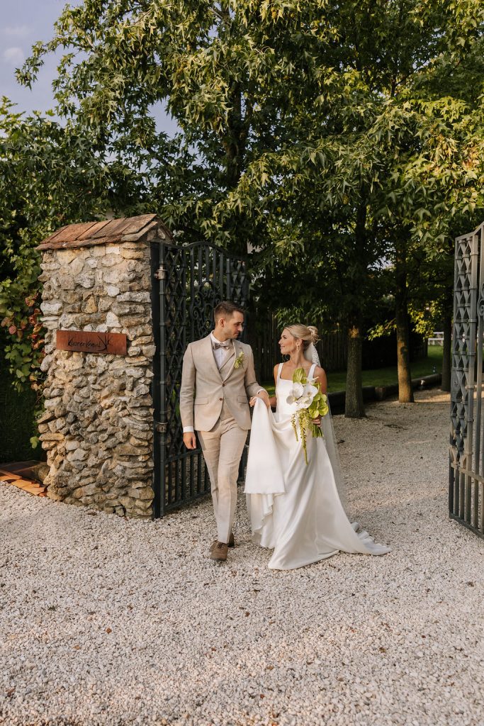 Braut in Brautkleid läuft mit ihrem Ehemann durch das Tor vom Kloster Kraul