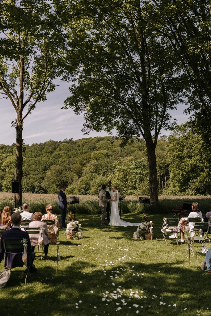 Kirche unter freiem Himmel. Brautpaar steht während der christlichen Hochzeit in der Mitte des Ganges und Hält sich die Hände Eventlocation Oefter Wald in Essen