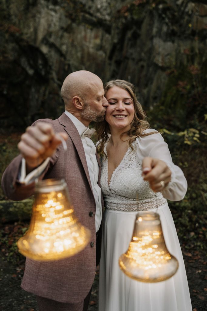 Brautpaar hält Laternen bei einem romantischen Fotoshooting im Wald im Neandertal in Erkrath.