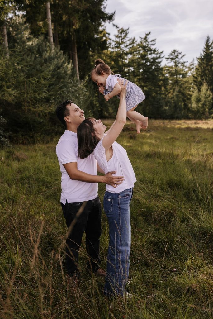 Fotografie Familie in Düsseldorf zeigt Eltern die ihr Kind hochheben während ein spielerischer und liebevoller Moment entsteht